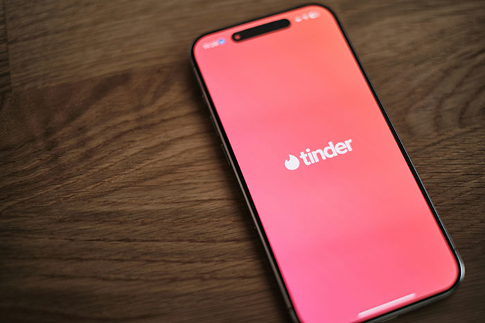 Tinder app on a smartphone screen, highlighting online dating and potential catfishing risks. Tinder app on a smartphone screen, highlighting online dating and potential catfishing risks.
