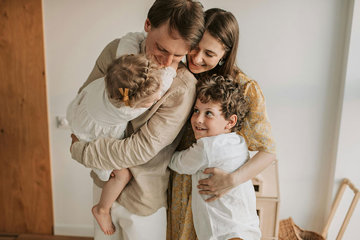 A happy family embracing, illustrating a "happily ever after" moment together in a bright home setting.