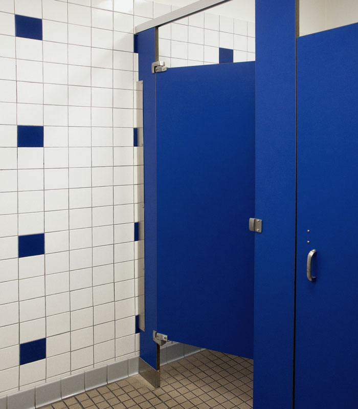 Public restroom with blue stall doors, highlighting concerns about hidden needle marks on toilet paper.