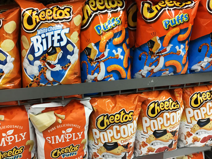 Cheetos snack bags on a shelf, highlighting different flavors like Puffs and Popcorn.