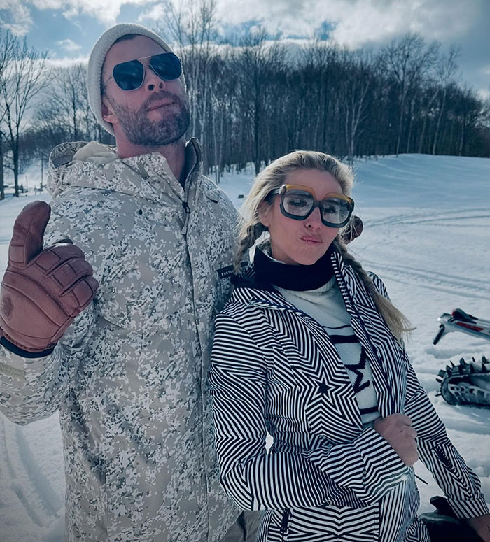Outdoor winter scene with two people in snow gear, wearing sunglasses, posing in snowy landscape. Outdoor winter scene with two people in snow gear, wearing sunglasses, posing in snowy landscape.