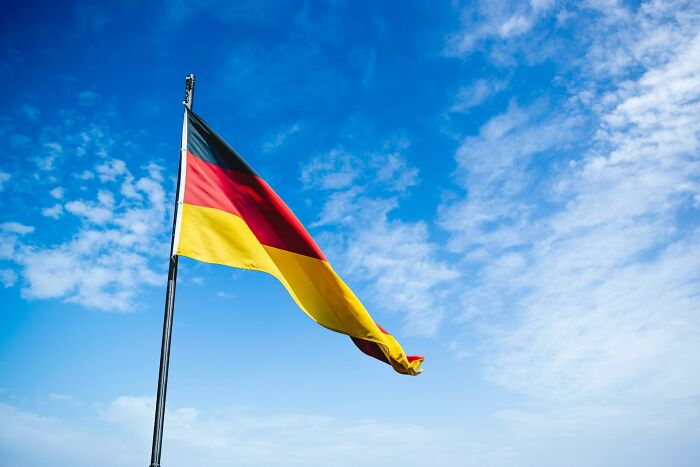 German flag waving under a clear blue sky, symbolizing European news stories.