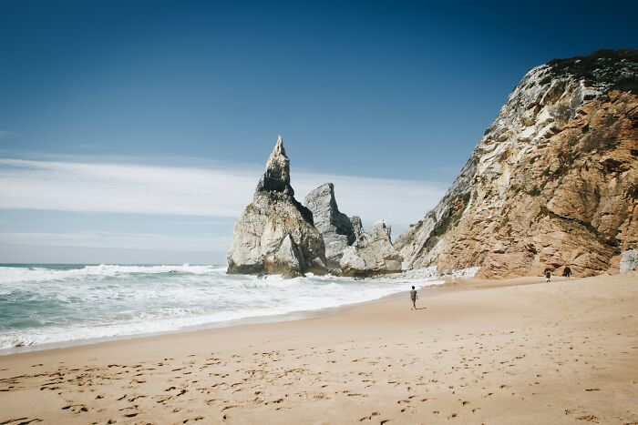 Stunning beach with sandy shore, blue sky, and towering rock formations perfect for travelers seeking adventure.