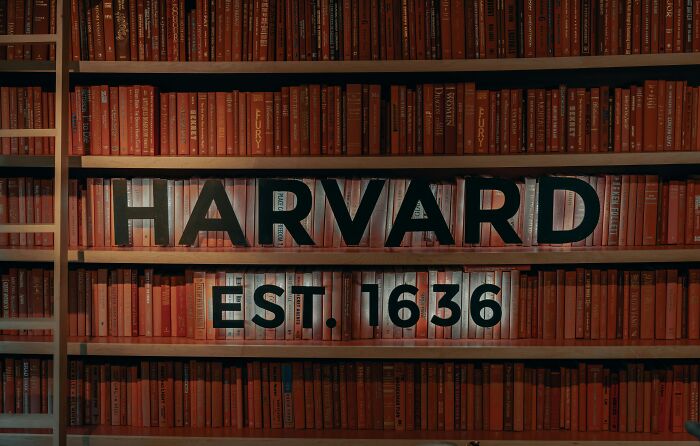 Harvard library backdrop with "Est. 1636" sign, highlighting free tuition announcement. Harvard library backdrop with "Est. 1636" sign, highlighting free tuition announcement.