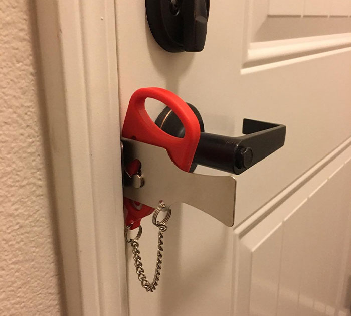Extraordinary travel door lock installed on a white door, featuring a red handle and chain for added security.