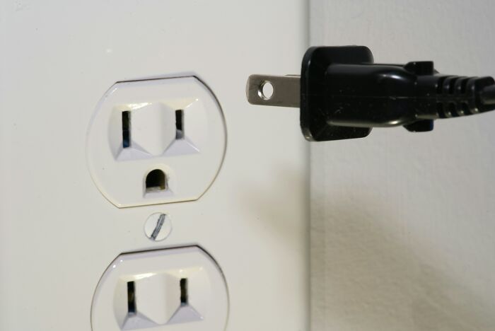 Plug next to an electrical outlet, symbolizing a historical turning point in technology and electricity use.