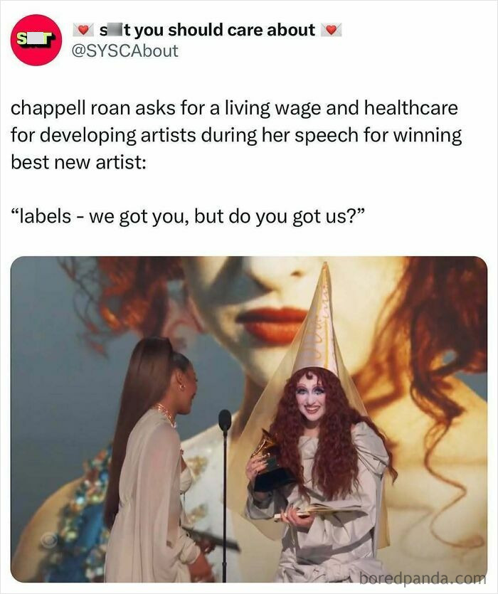 Woman in a hat holding award, discussing living wage and healthcare for artists on stage.