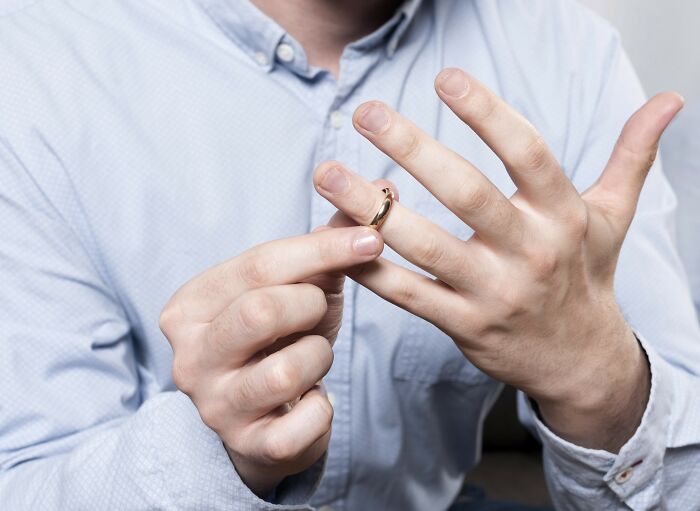 Man in blue shirt removing a ring, symbolizing a decision on what type to never date again.