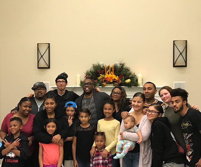 A large family gathered in front of a decorated mantel, smiling together for a group photo.