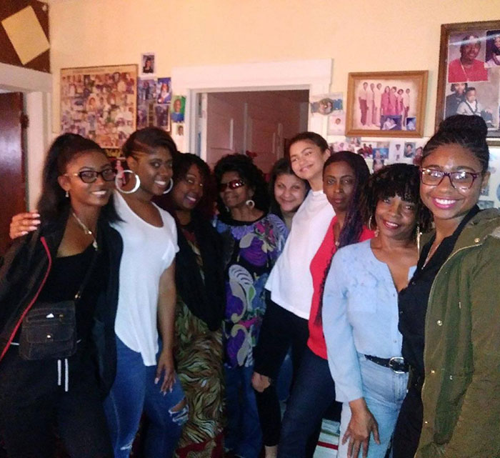 Group of women smiling indoors, in a room filled with family photos.