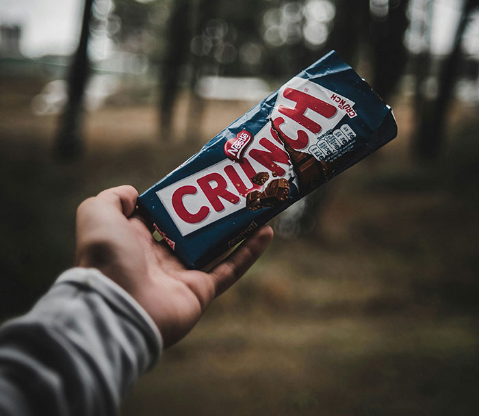 Person holding a Crunch chocolate bar outdoors, showcasing psychological trick of brand attraction.