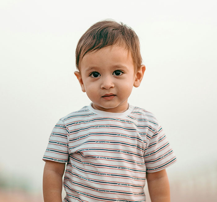 Toddler in a striped Lee Cooper shirt; subtle psychological cues in expression.