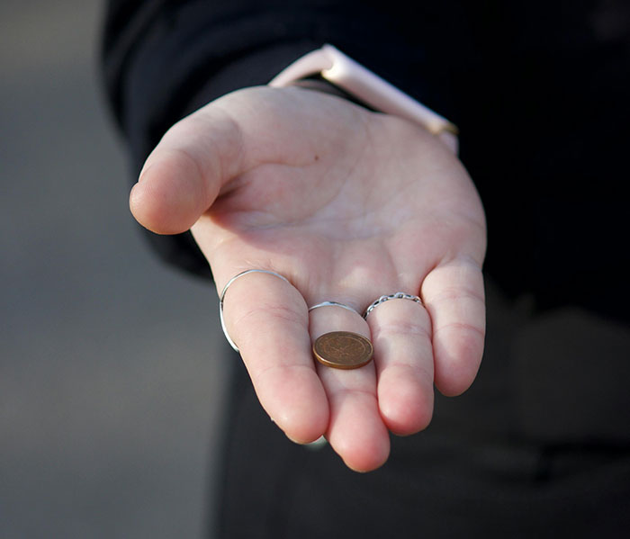 Hand displaying a small coin, illustrating psychological tricks and influence in everyday interactions.