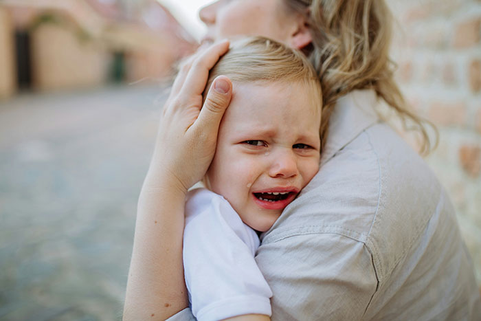 A child crying in a woman's arms, illustrating an emotional response, showcasing psychological tricks in emotional situations.