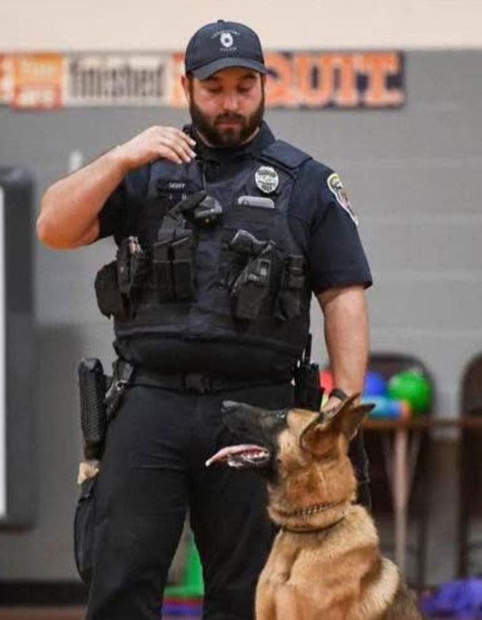 Police officer with service dog in uniform, inside a gym.