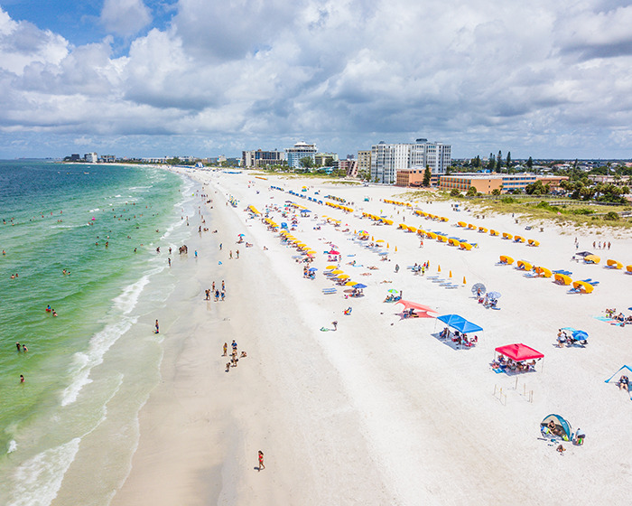 Aerial view of a crowded family swimming spot with people enjoying the beach and sea.