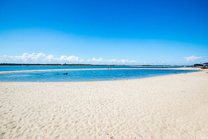 Sandy beach with a calm family swimming area under a clear blue sky.