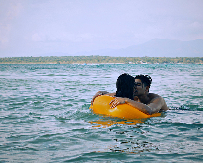 Couple embracing in the water at family swimming spot with orange inflatable.