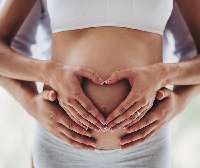Hands forming a heart on a pregnant belly, symbolizing support and connection during childbirth simulation experience. Hands forming a heart on a pregnant belly, symbolizing support and connection during childbirth simulation experience.