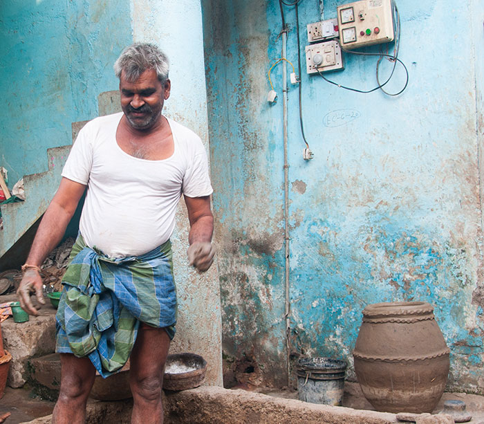 Man in traditional attire working with clay; example of unexpected cultural differences.