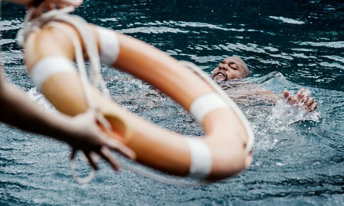 Person grasping for a lifebuoy in water, illustrating sudden dizziness awareness.