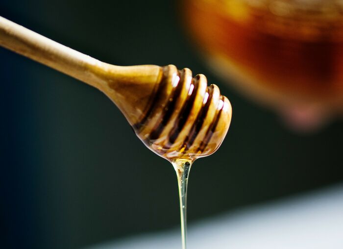 Honey drizzling from a honey dipper, illustrating one of the foods some people find disgusting.