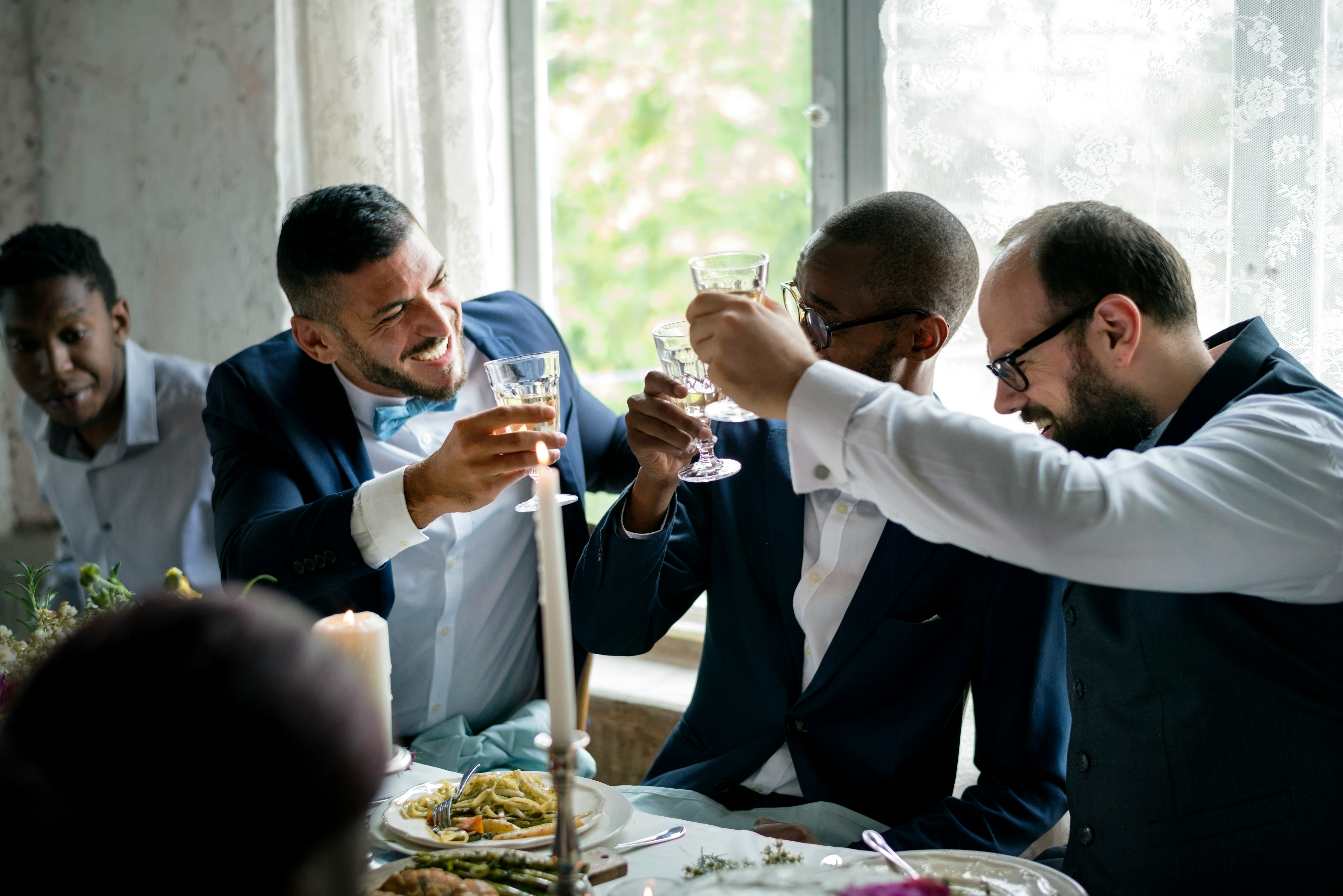 Men in suits celebrating with drinks during a birthday dinner.