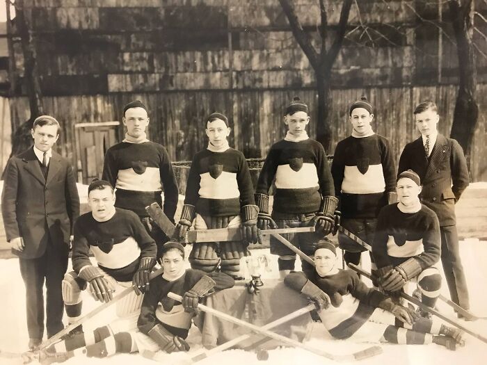 Vintage hockey team from 50-100 years ago posing outdoors, showcasing historical sports apparel.