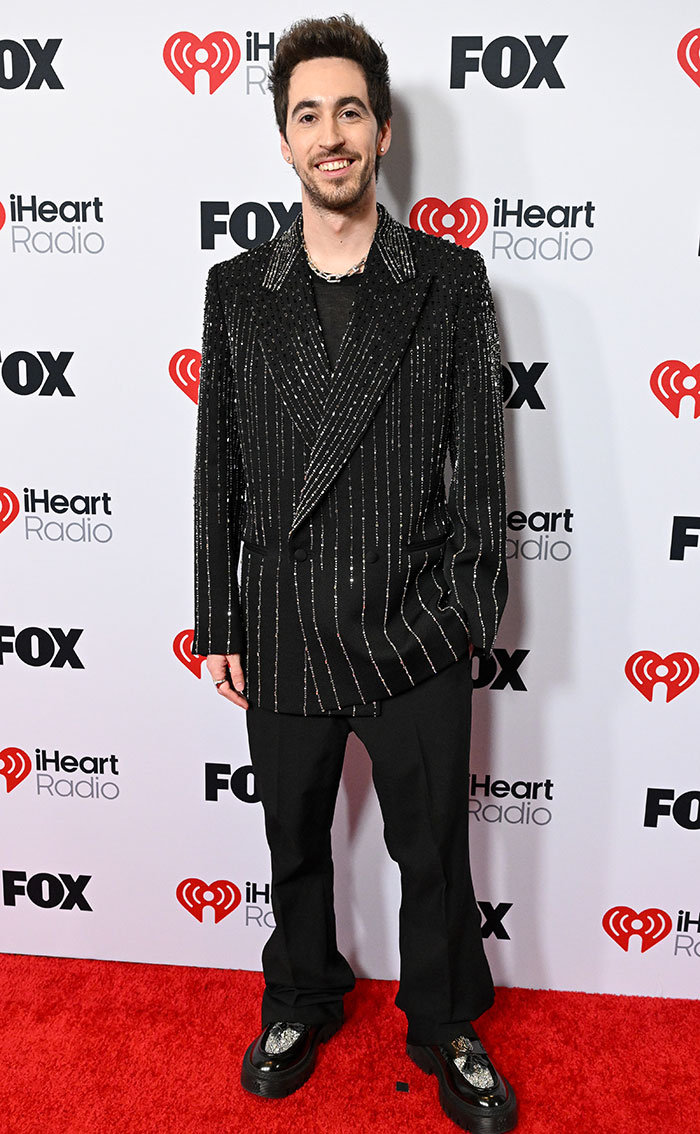 Man in a sparkly pinstriped suit on the red carpet at 2025 iHeartRadio Music Awards.