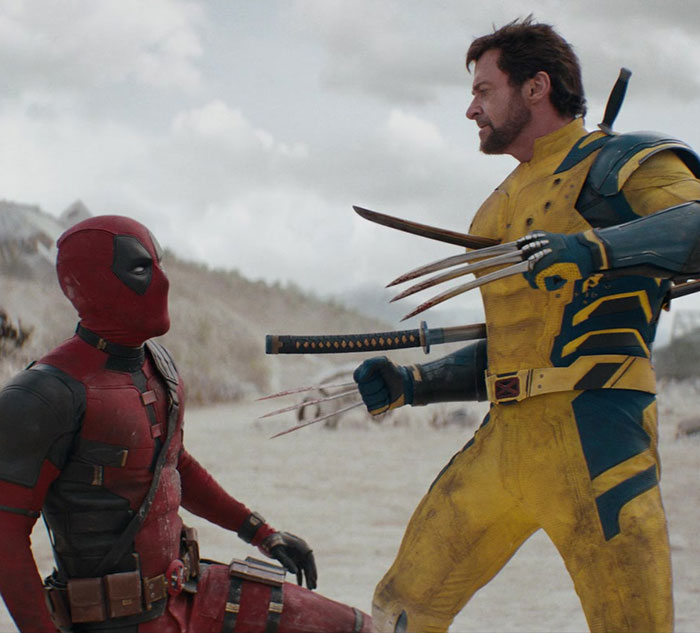 Hugh Jackman in Wolverine costume, confronting Deadpool in a snowy landscape.