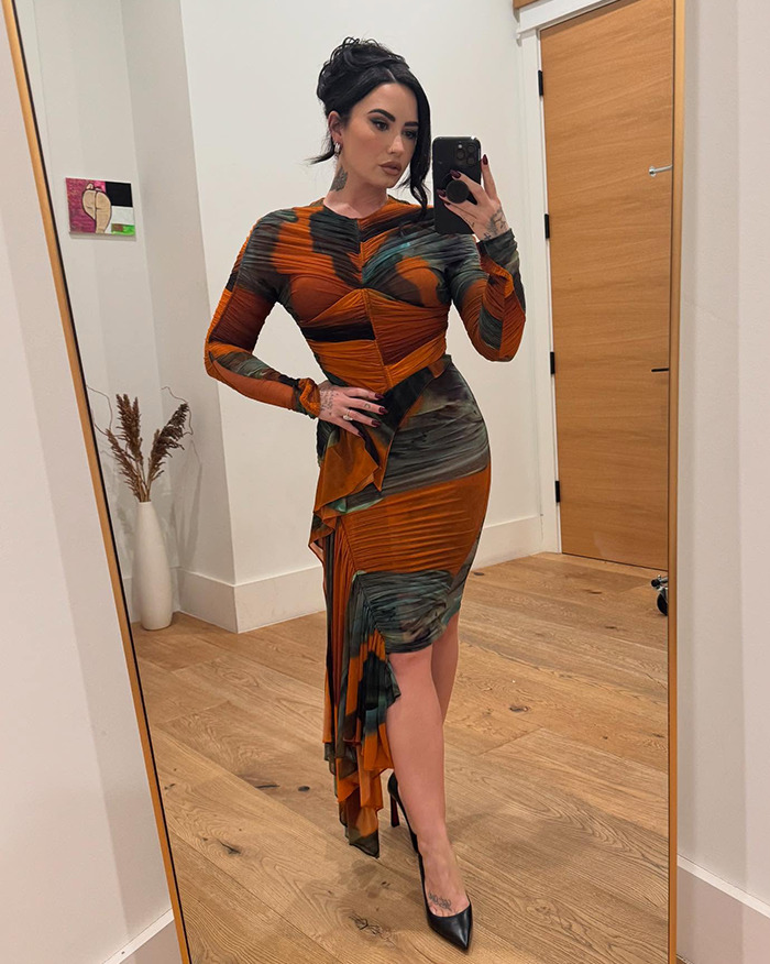 Person in elegant attire taking a mirror selfie, showcasing a weight loss transformation.
