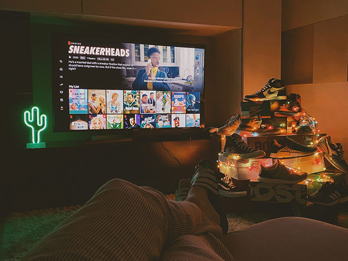Cozy living room setup with "Sneakerheads" on TV and a shoe display decorated with lights, showcasing brand themes.