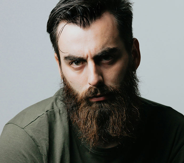 Man with a beard and intense expression, wearing a green shirt, fitting the description of an ex as a brand.
