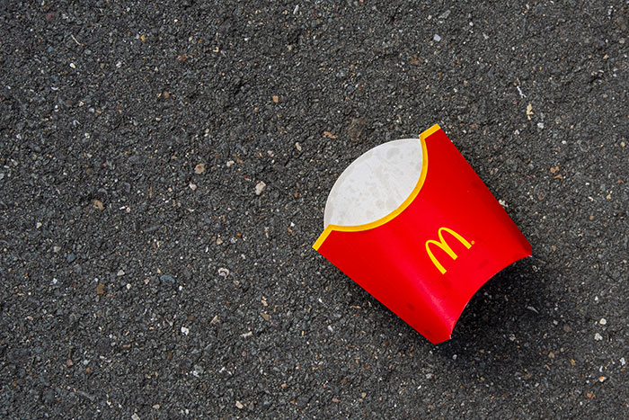Empty McDonald's fry carton on asphalt, symbolizing an ex as a brand.