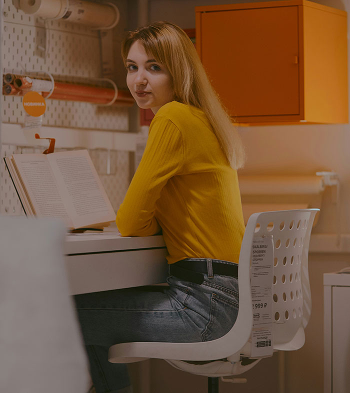 Person in yellow shirt sits at desk with open book, embodying a thoughtful brand concept.