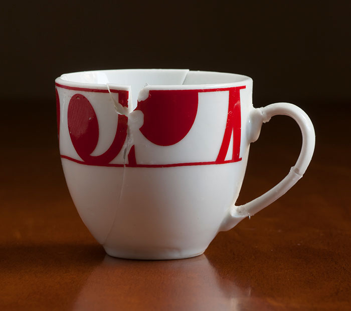 C*****d coffee cup with red design on a wooden table, symbolizing a broken brand.