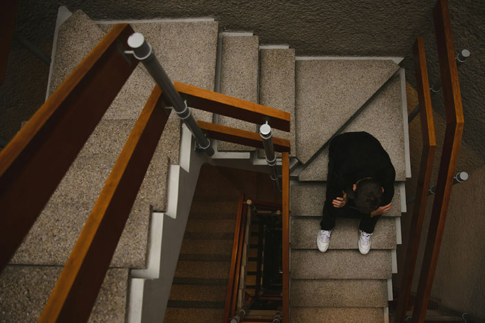 A person sitting on gray stairs, emphasizing the concept of describing ex-partners as a brand.
