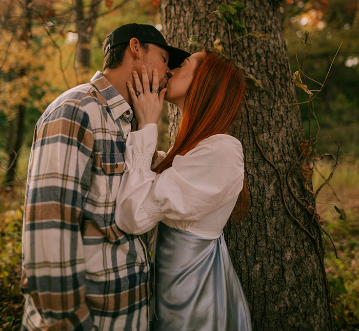 A couple sharing a kiss outdoors, illustrating a romantic brand-like connection.