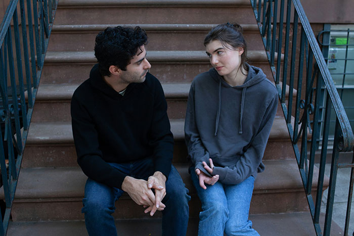 Two people sitting on stairs, engaged in a serious conversation, depicting a brand discussion about an ex.