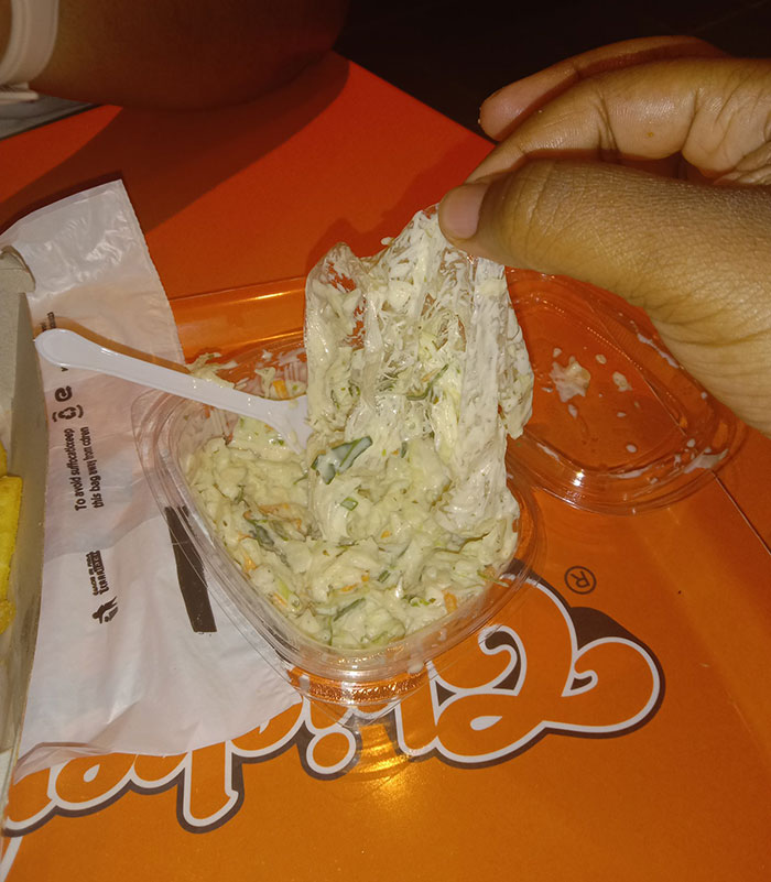 Person lifting a gooey clump from a food container, highlighting a failed attempt at enjoying a meal.