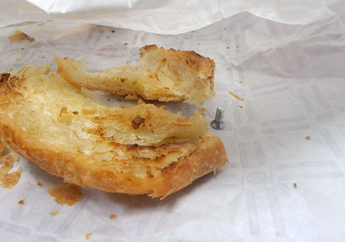 Pastry with a metal s***w found inside, revealing a disgusting surprise while trying to enjoy food.