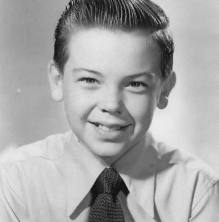 A young boy in a vintage portrait, smiling in a shirt and tie, representing things people find wholesome.