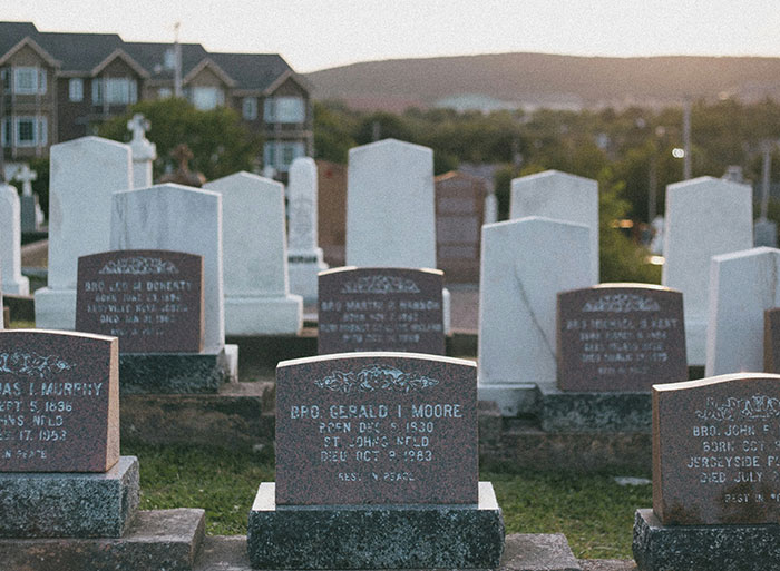 Gravestones in a cemetery at sunset, representing unexpected family secrets revealed by DNA tests.