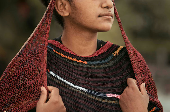 Person wearing a colorful poncho with a thoughtful expression, highlighting unexpected family secrets theme.