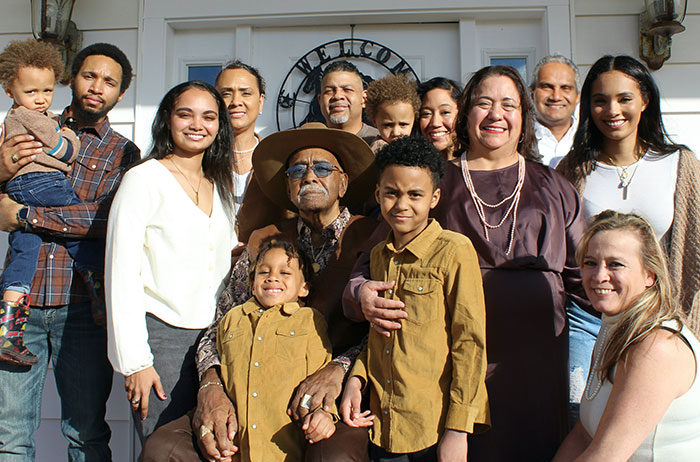 Family poses together outside a house, highlighting diverse expressions related to unexpected DNA test revelations.