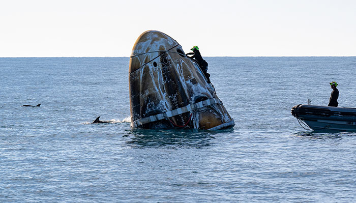Doctors assisting stranded astronauts at sea with a recovery capsule.
