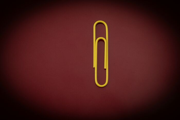 Yellow paper clip on a dark red background, symbolizing historical turning points in humanity.