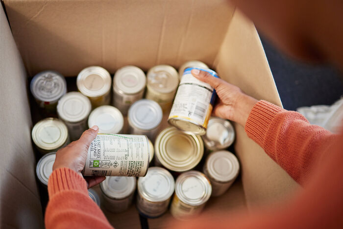 Person sorting canned goods in a box, highlighting a news story Europeans might share.