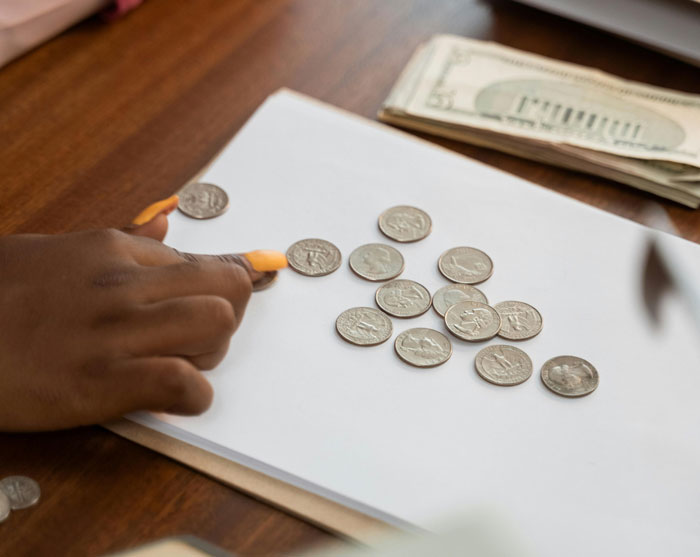 Person counting coins on a table next to money, illustrating a driver's petty revenge over paid tolls.