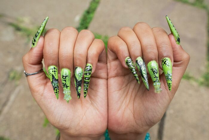Long green nails with black designs and "brat" text illustrating worst job interview experiences with HR.